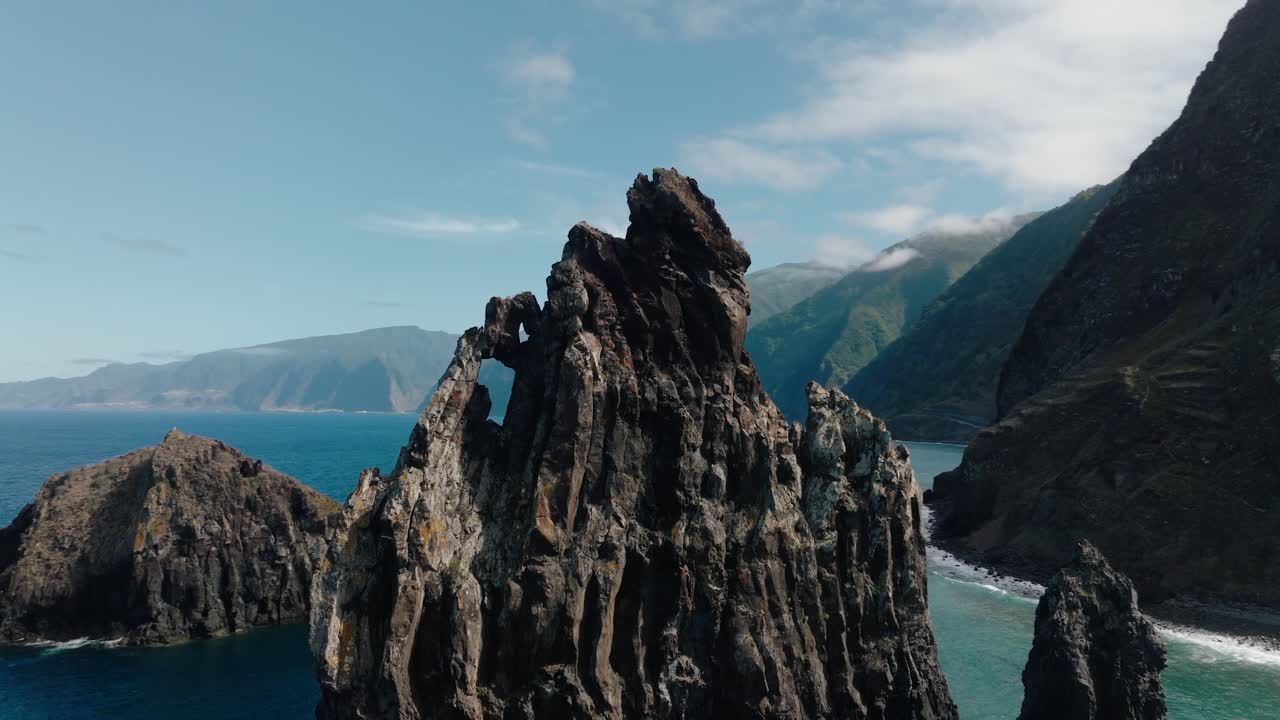 Aerial orbit of Madeira’s iconic rock arch at Ilhéus da Ribeira da Janela, with lush cliffs and turquoise waters stretching across the coastline.