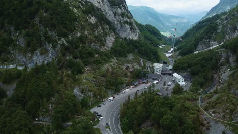 Aerial-view-drone-flight-at-the-scenic-mountain-serpentine-road-at-Plöckenpass-in-the-natural-Austrian-Italian-alps-at-the-border-in-summer-with-an-energy-windmill-turning-from-the-wind-in-nature
