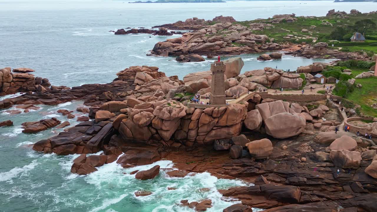 Receding drone movement from the popular Men Ruz lighthouse at the Côte de Granit Rose iconic tourists space, Ploumanac'h, Brittany, France