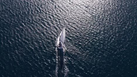 Segelschiff,-Das-Den-Tiefblauen-Ozean-Erkundet,-Mit-Strahlendem-Sonnenschein,-Der-Sich-Auf-Der-Oberfläche-Widerspiegelt