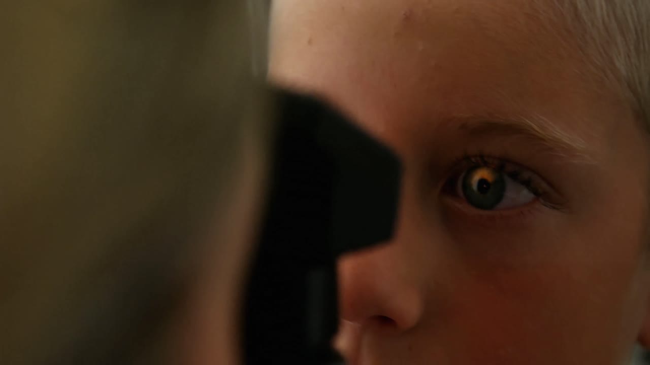 una optometrista examinando a un paciente joven con un oftalmoscopio