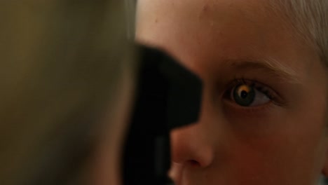 female optometrist examining young patient with ophthalmoscope