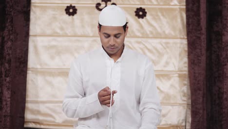 indian muslim man praying beads at home