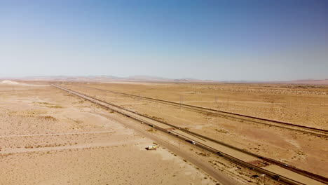 Aerial-view-of-a-long-straight-highway-stretching-through-a-barren-dessert-on-a-sunny-day