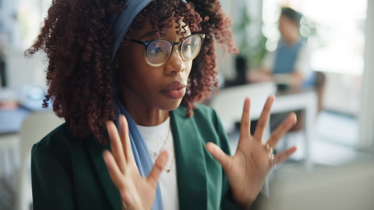 Junge afroamerikanische Frau setzt Brille auf und arbeitet im Büro