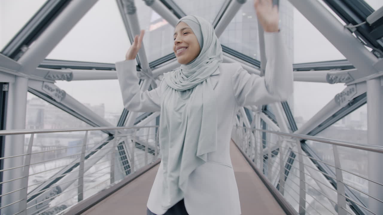 Smiling Woman in Hijab Walking on a Modern City Bridge