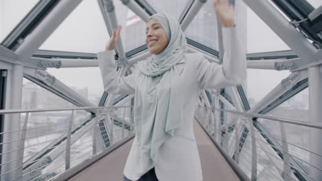 smiling woman in hijab walking on a modern city bridge