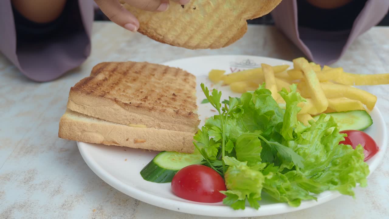 mujer comiendo un sándwich de queso a la parrilla con papas fritas y ensalada