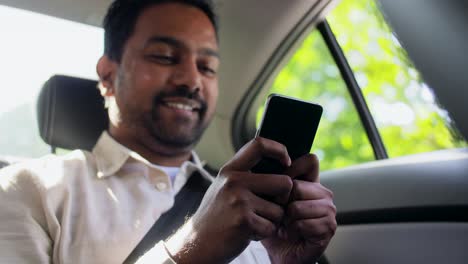 Pasajero-Masculino-Llamando-Por-Teléfono-Inteligente-En-Un-Taxi.-Concepto-De-Transporte,-Negocios-Y-Tecnología.-Feliz-Y-Sonriente-Pasajero-Indio-O-Empresario-Usando-Una-Grabadora-De-Comandos-De-Voz-En-Un-Teléfono-Inteligente-En-El-Asiento-Trasero-De-Un-Taxi.