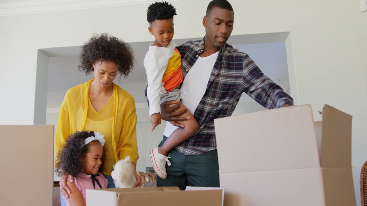 Front view of black family unpacking cardboard boxes at comfortable home 4k