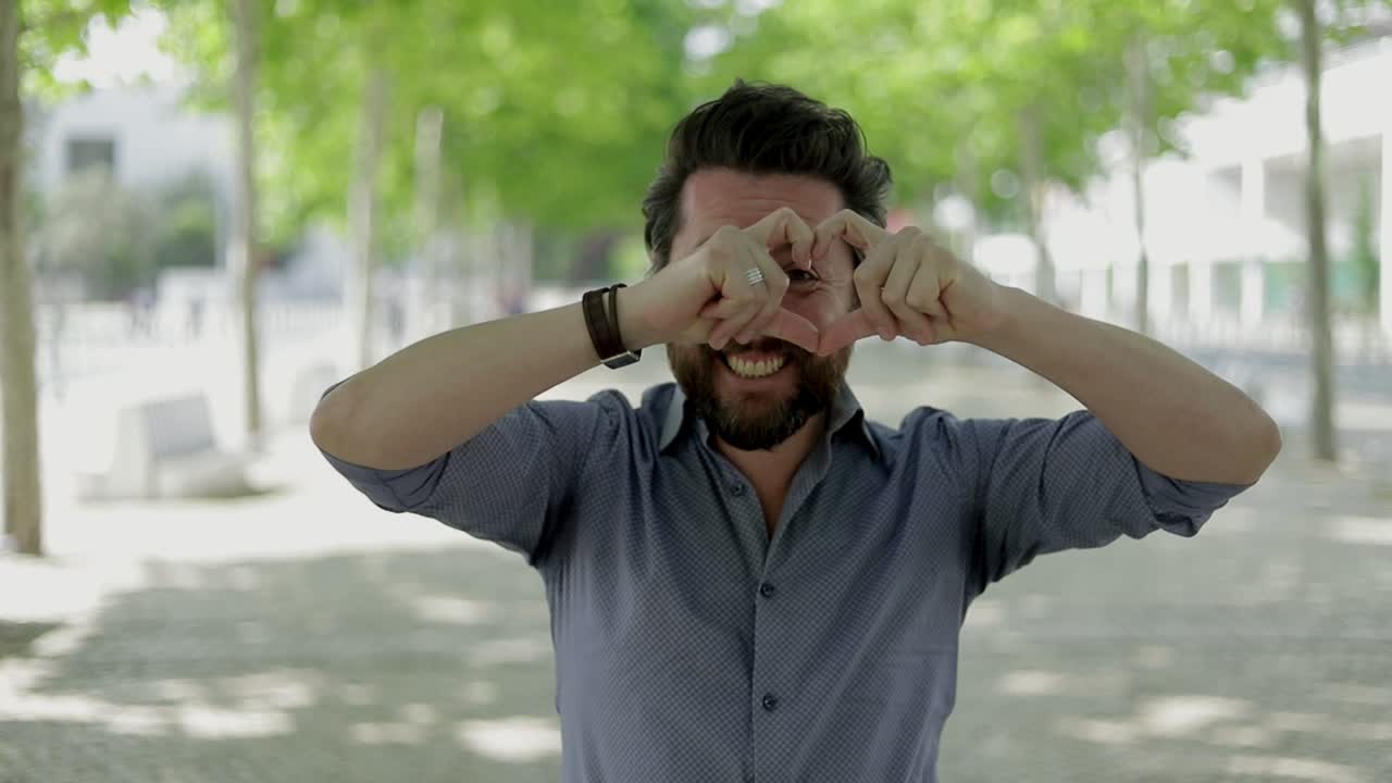 hombre feliz mostrando el símbolo del corazón de la mano al aire libre