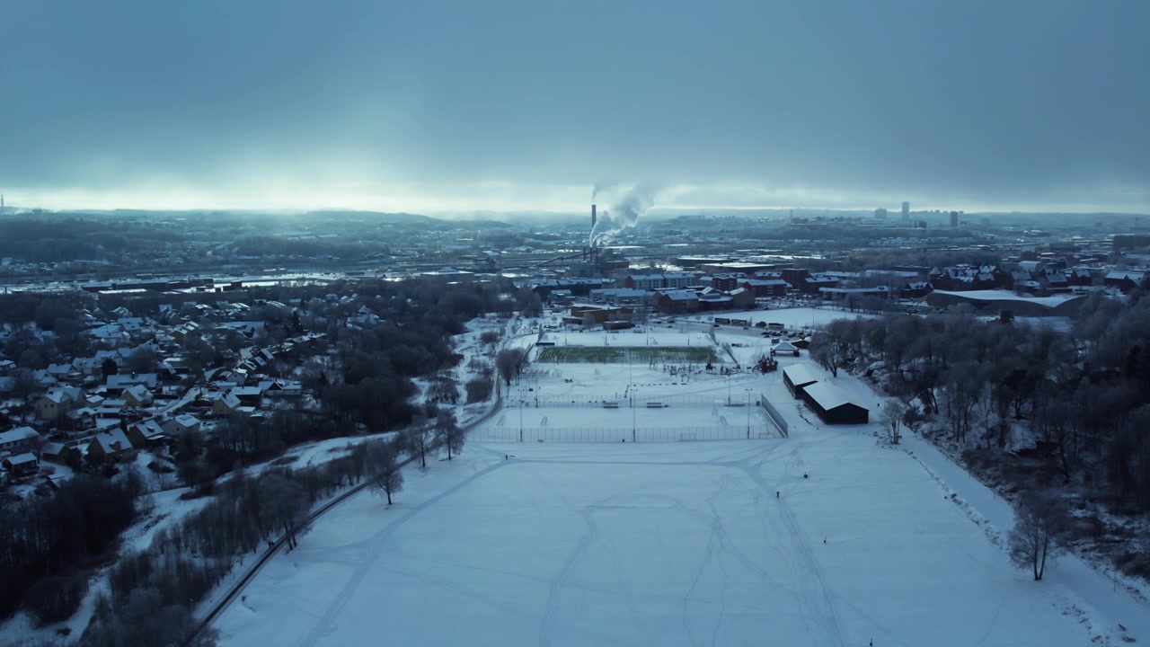 Kviberg Park winter fields and sports grounds with Gothenburg skyline, Sweden, drone establishing slow approach