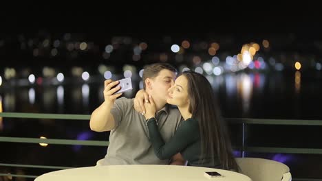 couple taking a romantic selfie at night with city lights in the background