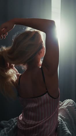 woman stretching in pajamas near window