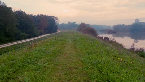 path with lake view and a single road bordering it at foggy autumn morning in central europe