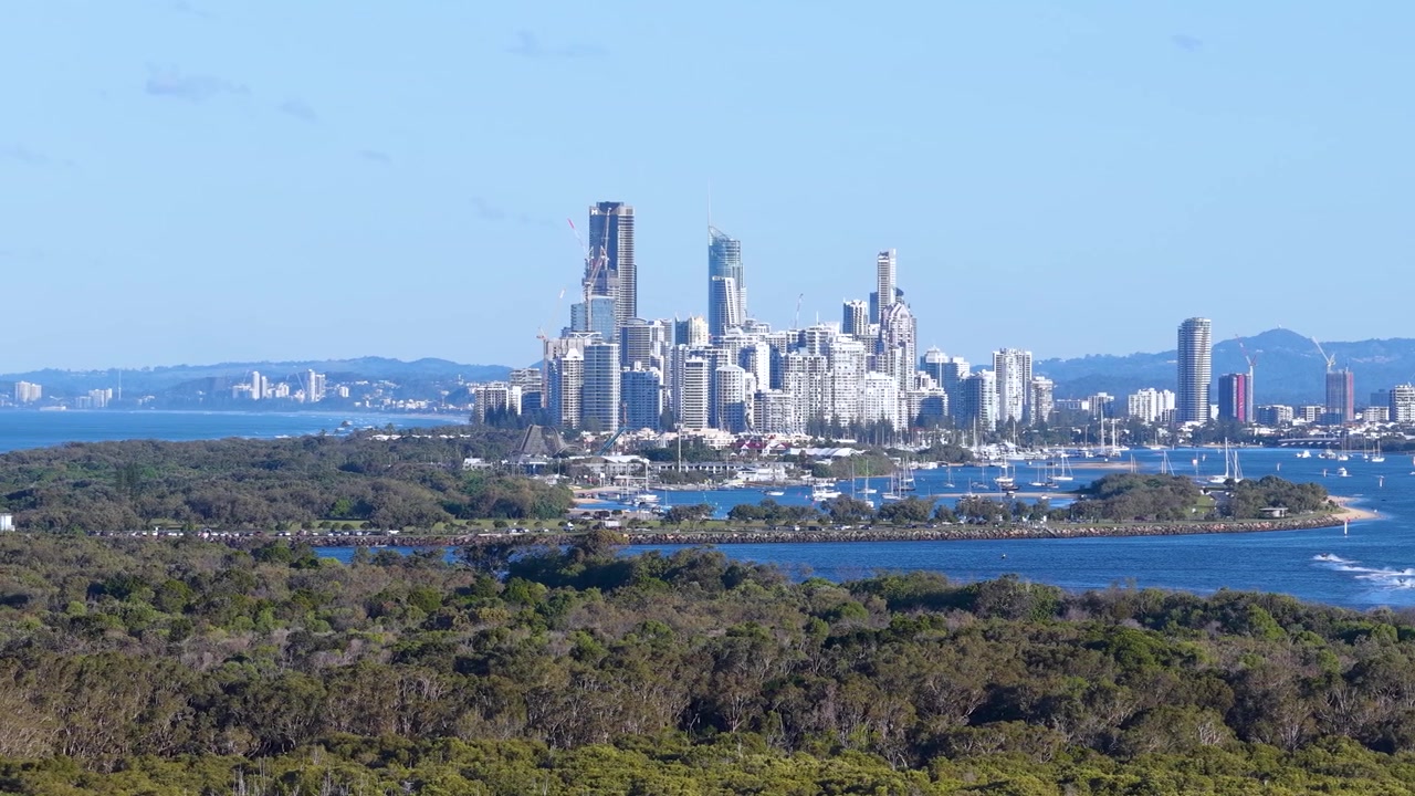Bredt panoramafoto af Gold Coast skyskrabere og hav bag frodigt grønt skovdække.