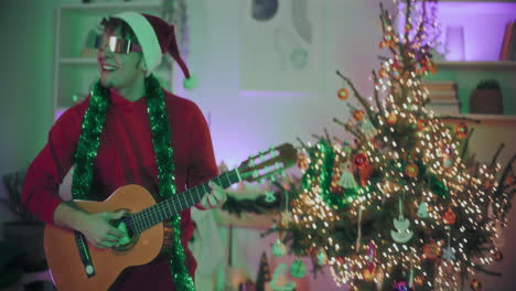 hombre bailando mientras toca la guitarra en una casa iluminada durante la navidad