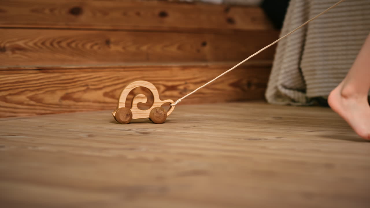 Little girl playing with a wooden snail rolling toy on the floor. Ecological and sustainability concept