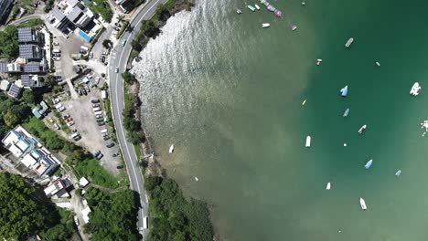 Traffic-on-the-Road-in-Sai-Kung,-Hong-Kong-nearby-Bay-with-Boats,-Drone-View