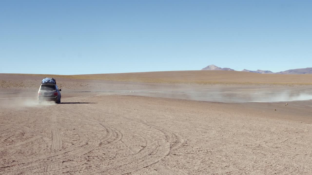 Travelers in SUV drives across the vast, arid terrain of Bolivia Sud Lipez region, surrounded by dry heat