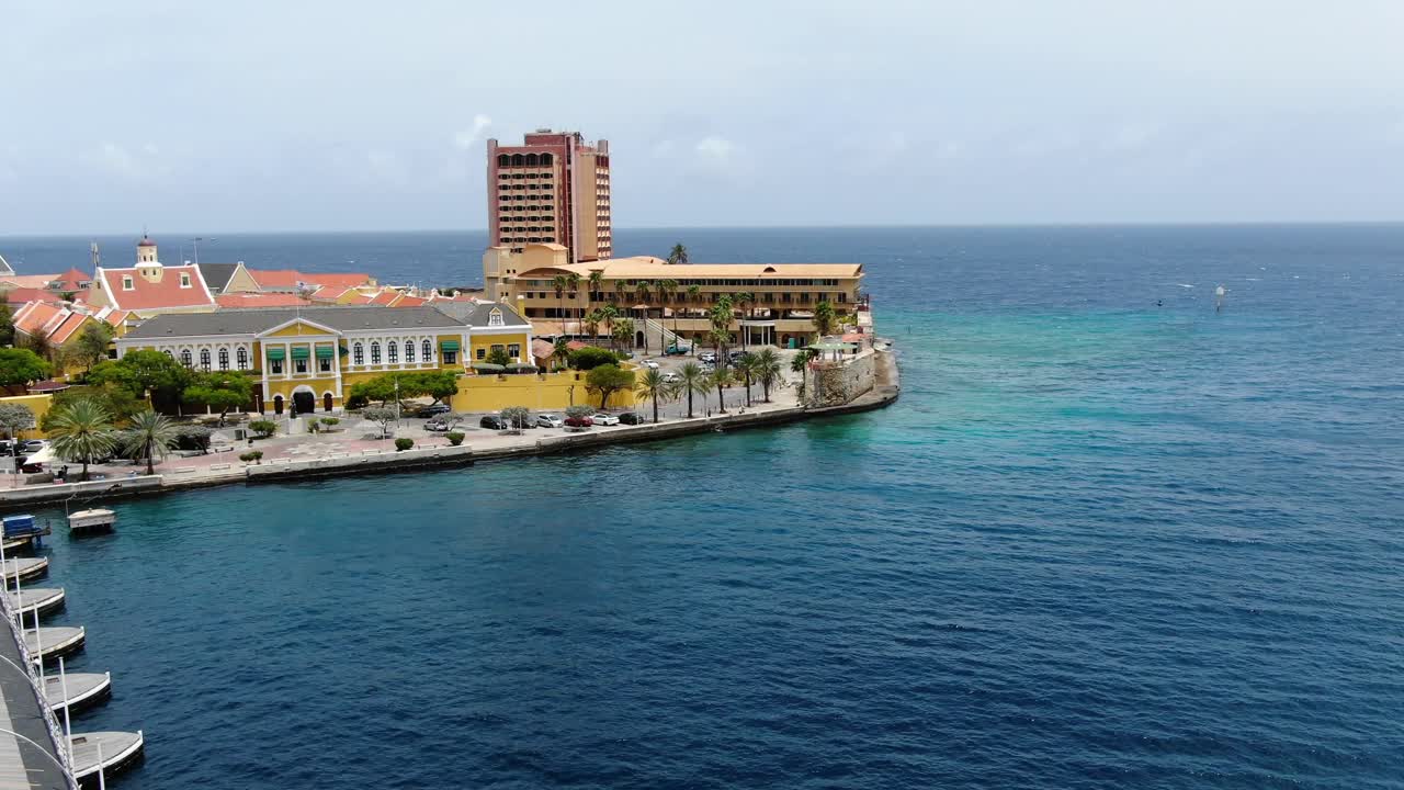 Aerial pullback along famed pontoon bridge of Willemstad Curacao and historic government buildings