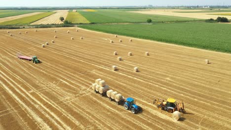 überblick über ein ackerfeld, wo man runde strohballen sammelt