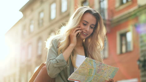 bottom view of blonde young woman talking on the phone while walking the city holding a map