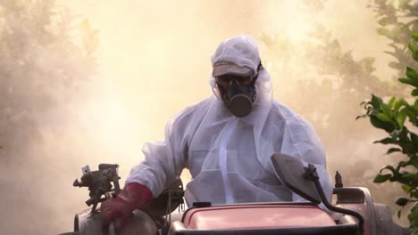 anonymous farmer spraying pesticide on lemon trees while riding tractor