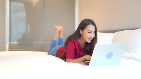 A-young-woman-lying-on-her-stomach-on-her-hotel-suite-bed-proves-that-work-from-anywhere-is-what-travelers-on-their-laptop-are-looking-for