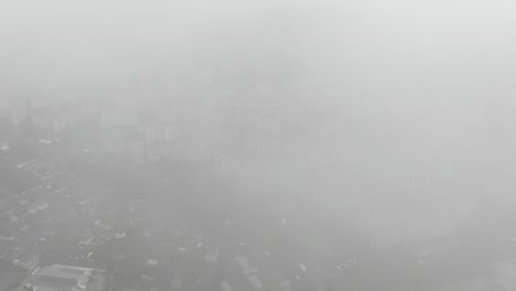 aerial view of dense cityscape slowly ascending through clouds