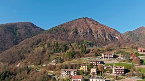 el dron se desliza suavemente justo sobre un pintoresco pueblo montañoso italiano, bañado por la luz del sol de otoño.