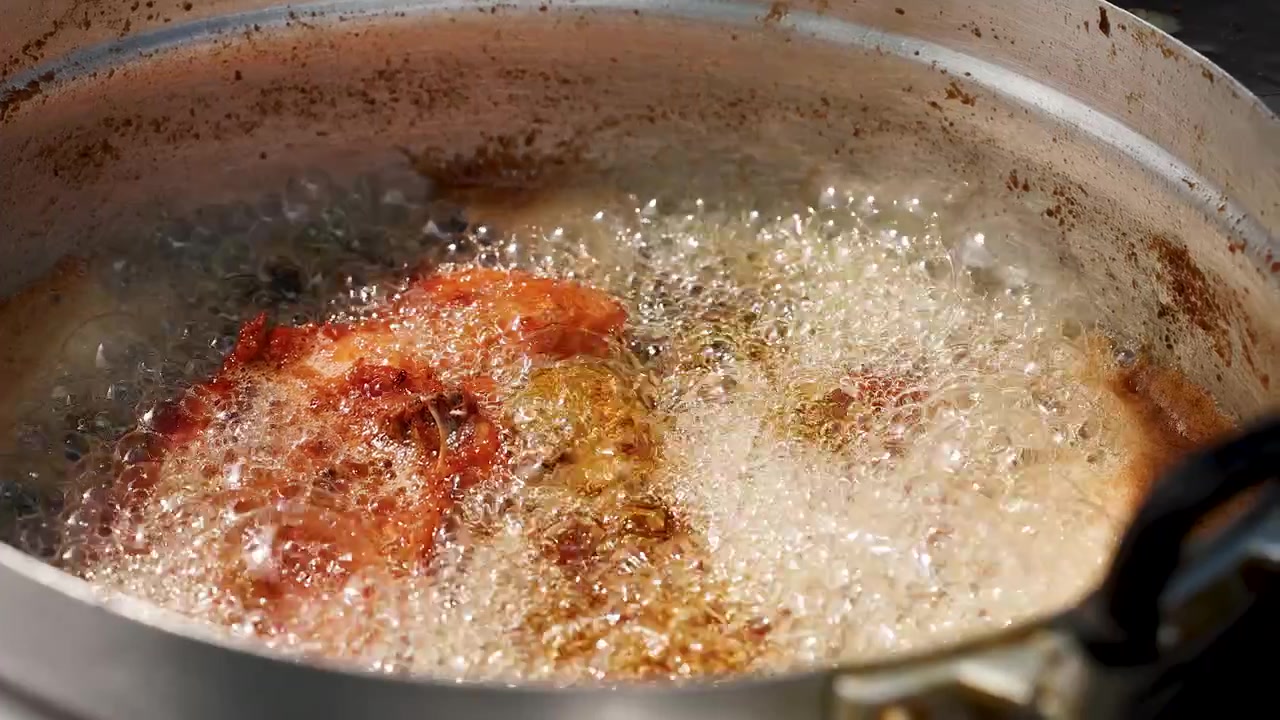 Friturestegning af kylling i varm olie i en metalgryde