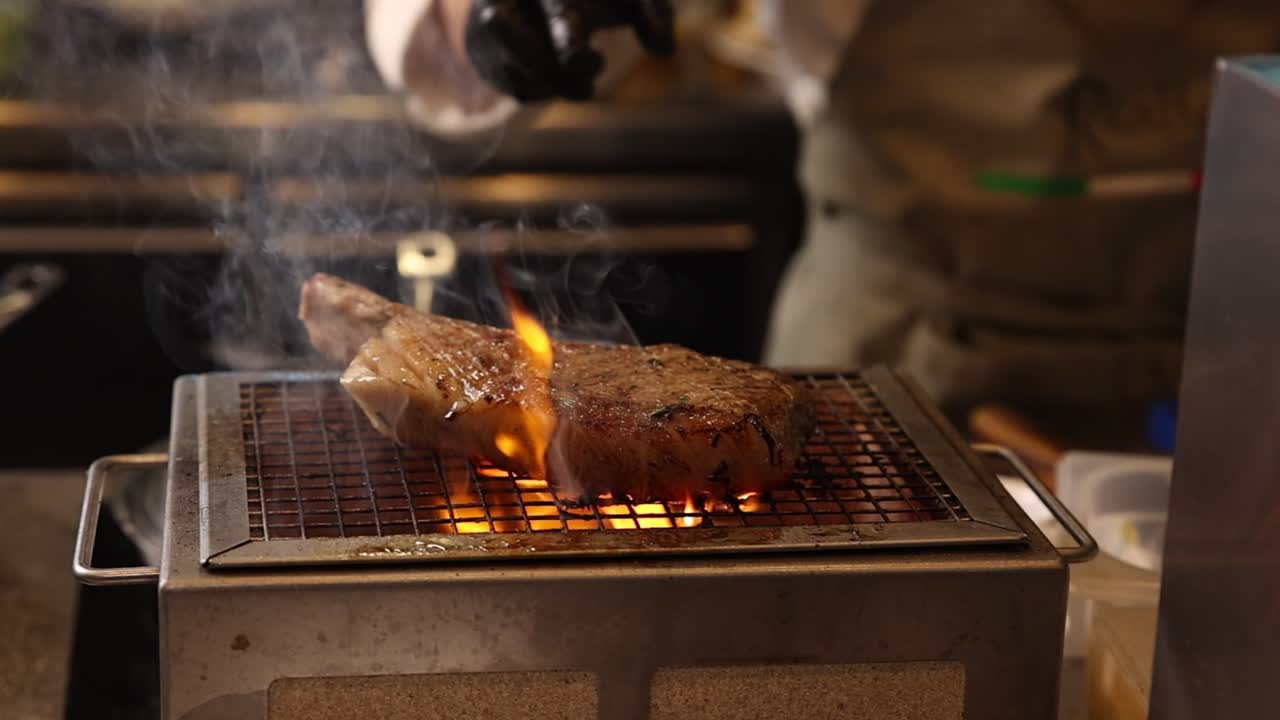 Grande bistecca alla griglia su fiamme vive in una cucina professionale