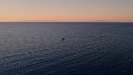 drone desciende a un barco de pesca en el océano abierto, nadie más a la vista, hora dorada cielo del atardecer, ondas del océano en ángulo perpendicular