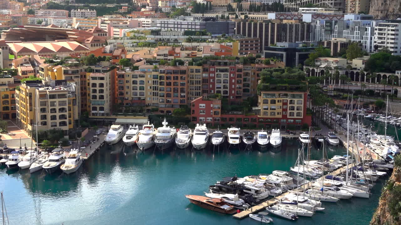High-angle view of Port de Fontvieille in Monaco, showcasing colorful buildings, luxury yachts, and the surrounding mountainous landscape