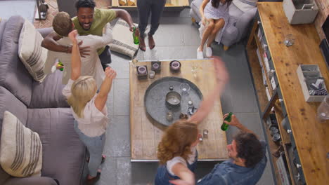 overhead shot of multi-cultural group of friends watching sports game on tv at home celebrating