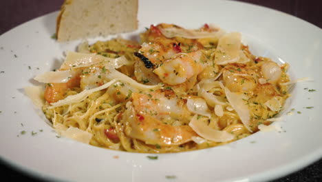 shrimp over angel hair pasta with focaccia bread and shaved parmesan sprinkled with herbs in white dish, slider 4k