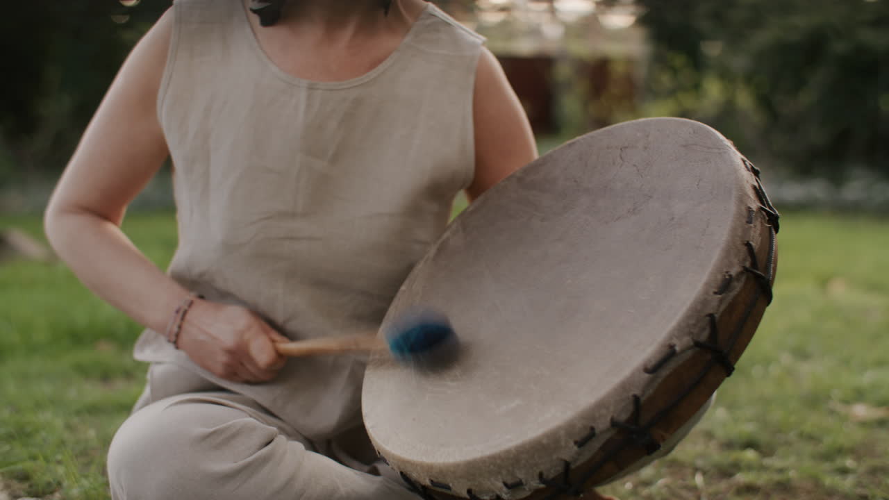 Woman playing a traditional drum in a garden
