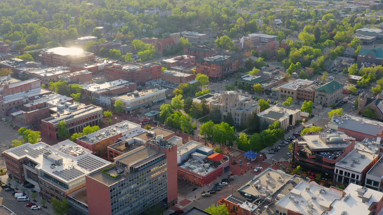 panorámica aérea a la derecha del centro de boulder colorado y pearl street con árboles verdes brillantes durante una puesta de sol nocturna con luz cálida en el paisaje de verano