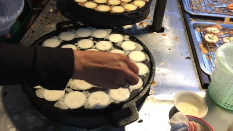 concepto de cocina. tipo de carne dulce tailandesa. leche de coco mezclada con postre frito en polvo en el mercado de comida callejera tailandés de la noche. postre de carne tradicional tailandesa, panqueque, pudín. imágenes de 4k.