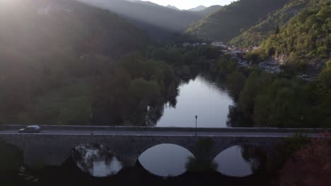 car is driving over a bridge at rijeka crnojevic montenegro, aerial