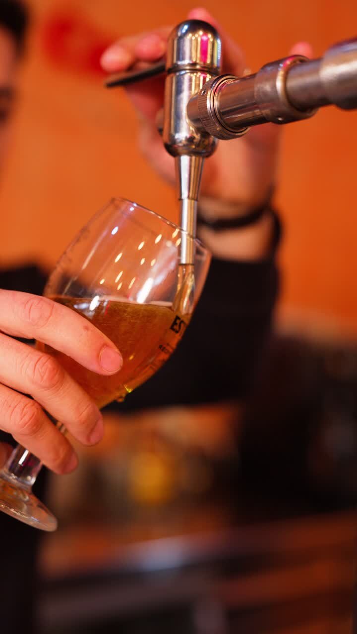 Primo piano di un barman che versa birra alla spina in un bicchiere