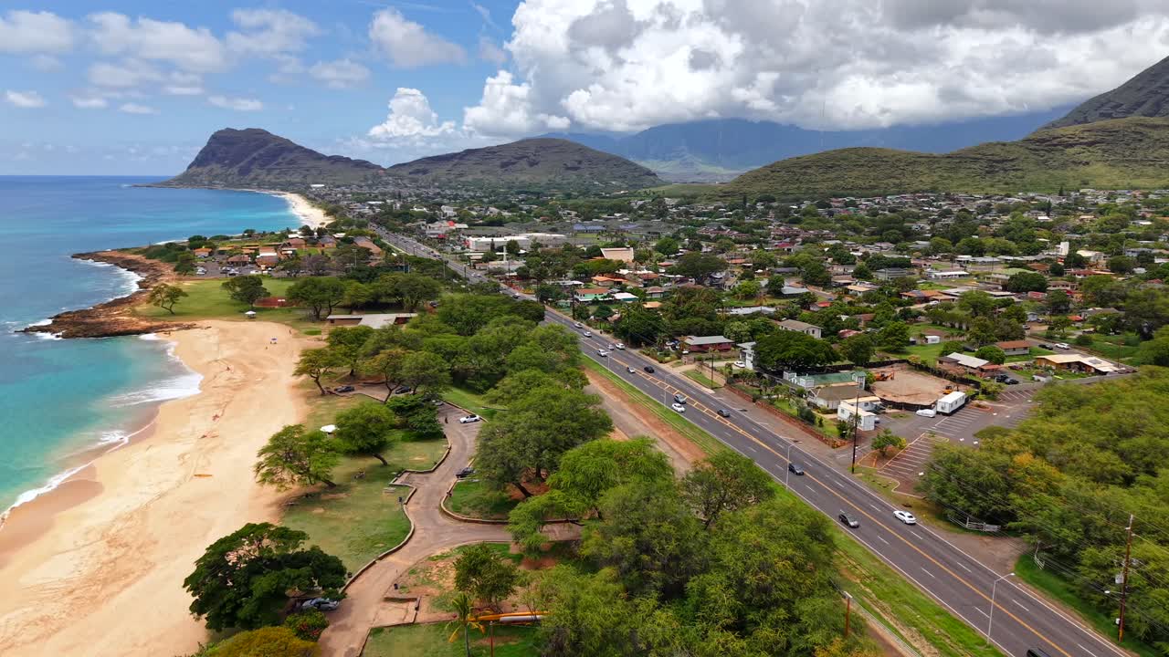 Cars drive on highway along Pōkaʻī Bay Beach in Waianae, Oahu