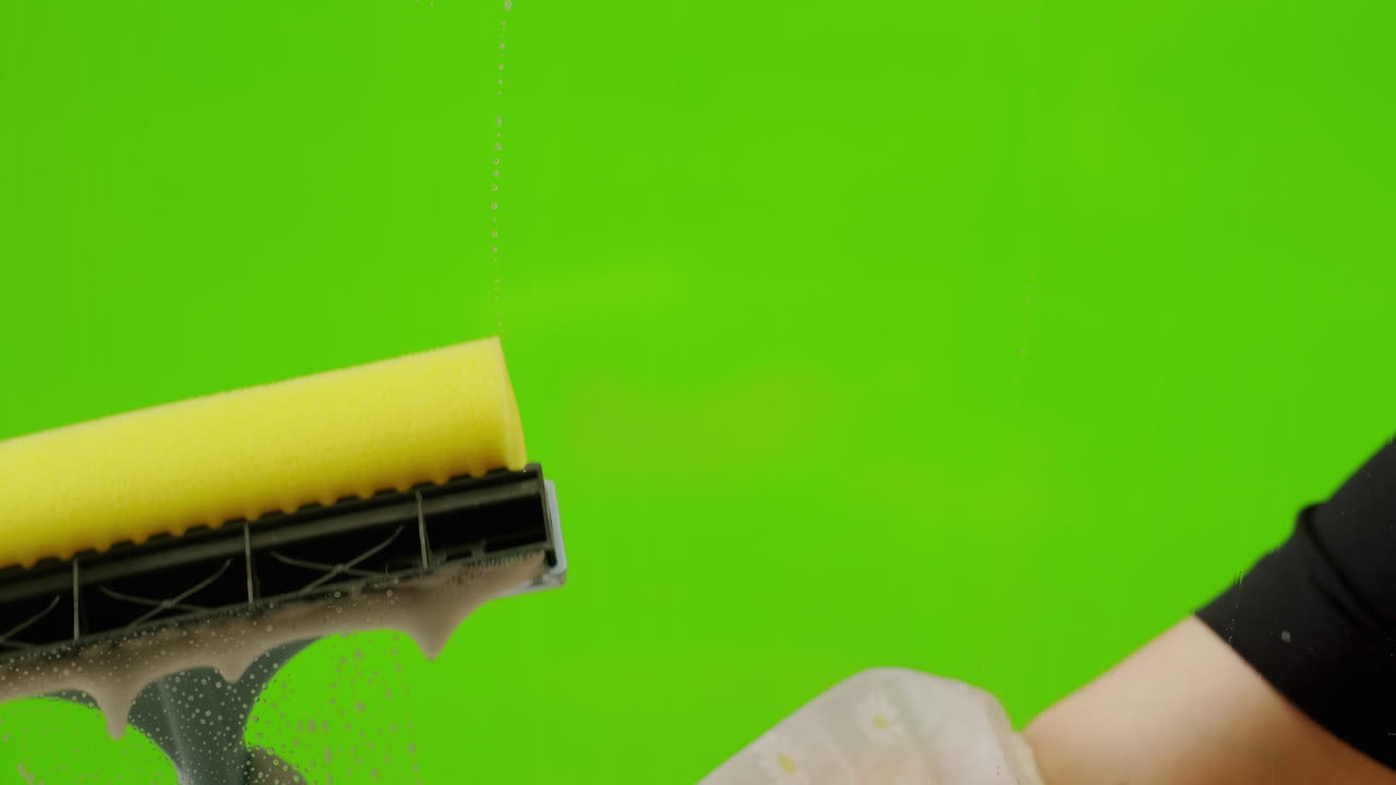 Primo piano di una mano che pulisce una superficie saponata con un tergivetro
