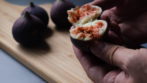 the hands of chef open fresh fig to reveal chewy red flesh and seeds inside in the kitchen.