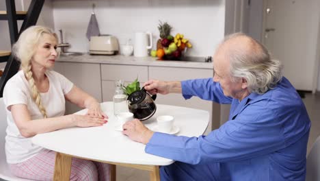 una pareja de ancianos disfrutando de café en casa.