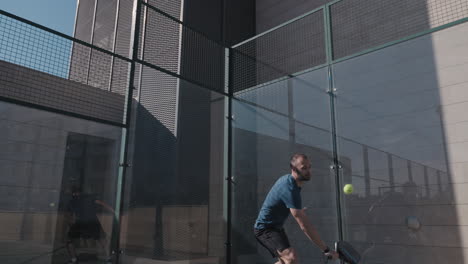 Padel-tennis-player-does-a-lob-shot-after-the-ball-hits-the-backwall