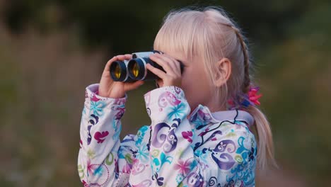 a cheerful child looks through binoculars 1