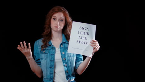 a young caucasian woman points at a paper saying &quot;sign your life away