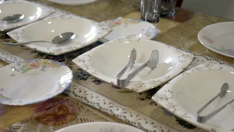 close up of a table setting with white plates and serving utensils